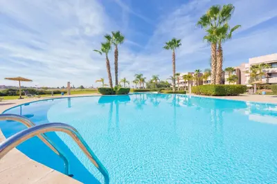 a large swimming pool with palm trees in a resort at Elevated Elegance A Stylish Golf Atlas Apartment in Marrakech