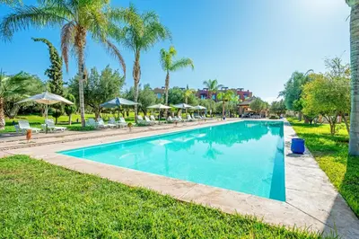a swimming pool with palm trees and grass at Luxury Apartment in Vizir Park & Resort in Marrakech
