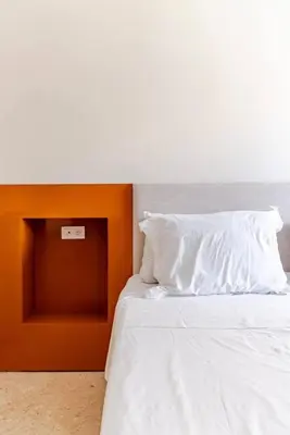 a white bed with an orange headboard and white pillows at Appart Chambre et Salon Gueliz Marrakech Alia1 in Marrakech