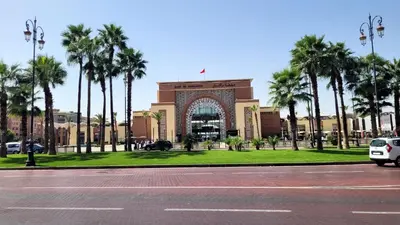 a building with palm trees in front of a parking lot at Le Confortable a 15mn de L'aéroport interdit au couples non marié in Marrakech