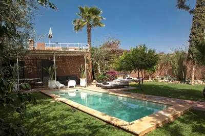 a swimming pool in a yard with a palm tree at Villa Em in Marrakech