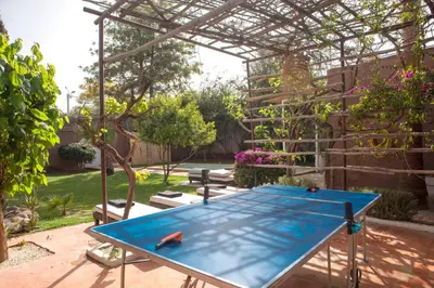 a ping pong table in a garden with a pergola at Villa Em in Marrakech