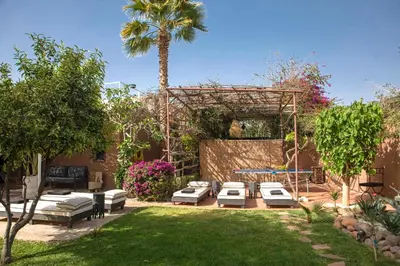 a backyard with lounge chairs and a palm tree at Villa Em in Marrakech
