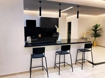 a kitchen with a black counter and three bar stools at Centre ville Gueliz Plaza Marrakech in Marrakech