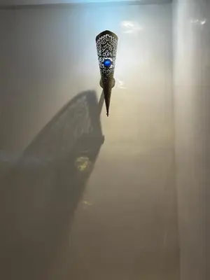 a peacock feather casts a shadow on a wall at Dar Nahila Appartement Aéroport in Marrakech