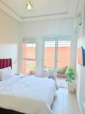 a bedroom with a white bed and a balcony at Charmant Studio B5 & Bel Terrasse in Marrakech