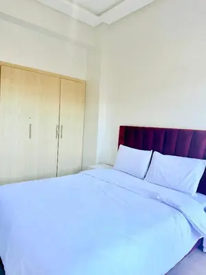 a bedroom with a large white bed and a cabinet at Charmant Studio B5 & Bel Terrasse in Marrakech