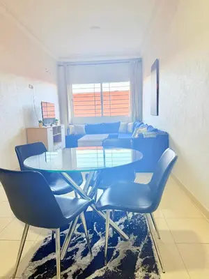 a dining room with a glass table and blue chairs at Charmant Studio B5 & Bel Terrasse in Marrakech