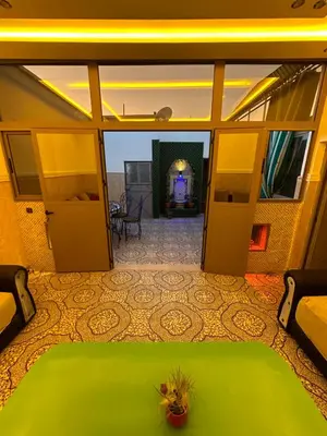 a view of a bedroom with a green bed and a living room at 5 min Aéroport Appartement avec Terrasse et Grand Appartement in Marrakech