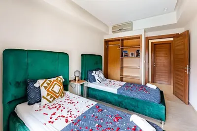 two beds in a bedroom with green headboards at la cocon paisible de Marrakech in Marrakech
