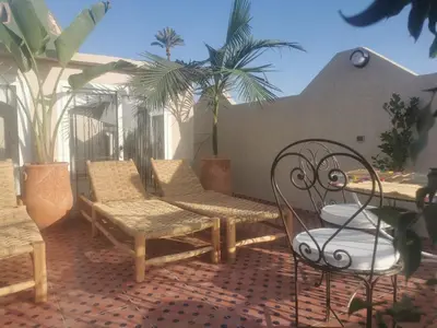 a patio with chairs and a table and palm trees at Riad Raphia in Marrakech