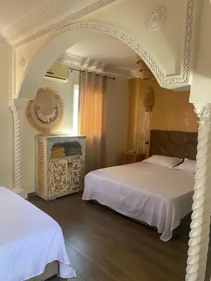 a bedroom with two beds and an archway at Riad Raphia in Marrakech