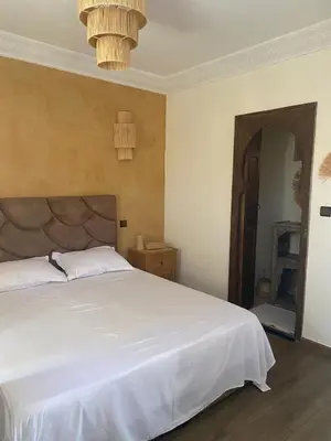 a bedroom with a large white bed and a chandelier at Riad Raphia in Marrakech