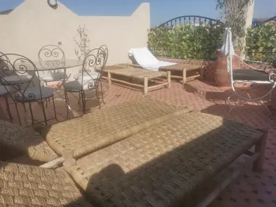 a patio with benches and chairs and an umbrella at Riad Raphia in Marrakech