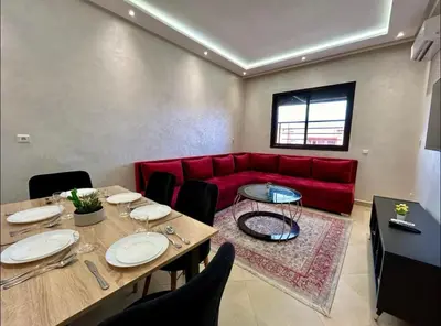 a living room with a red couch and a table at Chic Appartement Marrakech in Marrakech