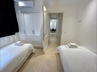 two beds in a white room with a hallway at Chic Appartement Marrakech in Marrakech