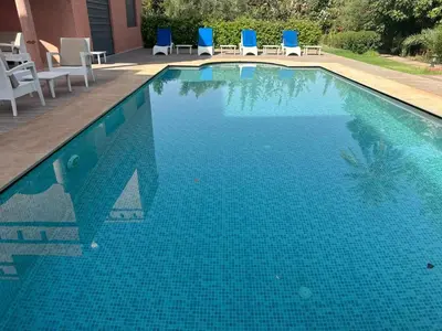 a large swimming pool with blue chairs in a yard at Villa à la palmeraie in Marrakech