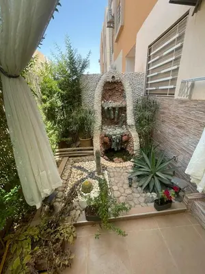 a garden with a fountain and some plants and a building at Appartement aux portes de Marrakech in Marrakech
