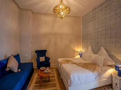 a bedroom with a bed and a chair and a chandelier at Riad Dar Al-Famila & Spa in Marrakech