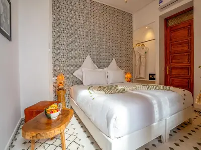 a bedroom with a large white bed and a table at Riad Dar Al-Famila & Spa in Marrakech