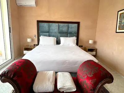 a bedroom with a large bed with two chairs at Palais Bahida in Marrakech