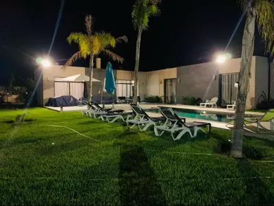 a group of lawn chairs next to a pool at night at Villa 4 chambres sans vis à vis in Marrakech