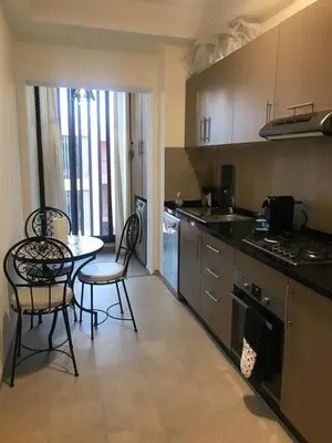 a kitchen with a table and two chairs and a table and a kitchen with at Luxueux Appartement Domaine de Noria, Wifi, Clim, Piscine, Résidence Privée in Marrakech