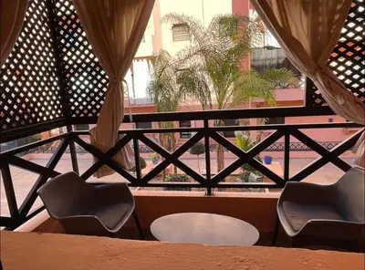 a balcony with two chairs and a table and a window at Appartement 5 piscine sport in Marrakech