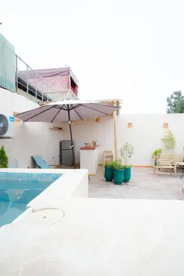 a patio with an umbrella and a swimming pool at Riad Lkhlil in Marrakech