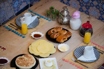 a wooden table with breakfast foods and drinks on it at Riad Lkhlil in Marrakech