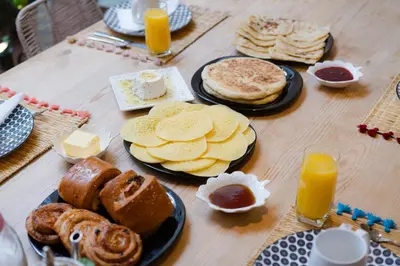 a wooden table topped with plates of bread and pastries at Riad Lkhlil in Marrakech