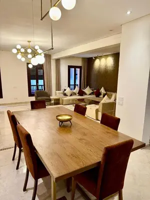 a dining room table with chairs and a living room at Plaza Guéliz Prestige Apartment in Marrakech