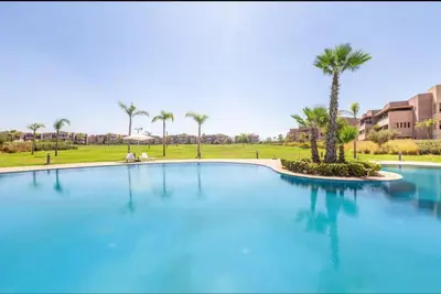 a large swimming pool with palm trees in the background at Ali plaza marrakech in Marrakech