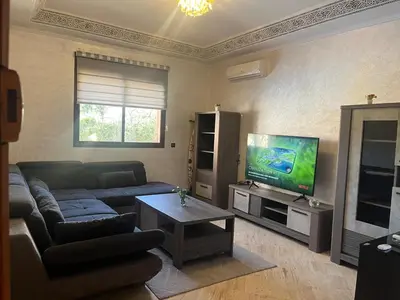 a living room with a couch and a flat screen tv at Appartement Central Marrakech in Marrakech