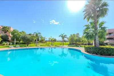 a large blue swimming pool with palm trees at Appartement Marrakech golfe in Marrakech
