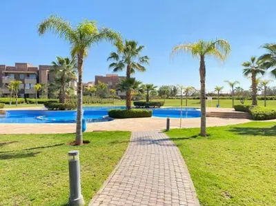 a brick walkway in a park with palm trees at Appartement Marrakech golfe in Marrakech
