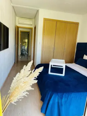 a bedroom with a bed with a blue bedspread and a white table at Appartement Marrakech golfe in Marrakech