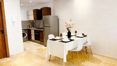 a kitchen with a white table with white chairs and a refrigerator at Appartement cosy Marrakech in Marrakech