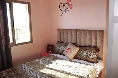 a bedroom with a bed with leopard pillows and a window at beautiful appartement near airport in Marrakech