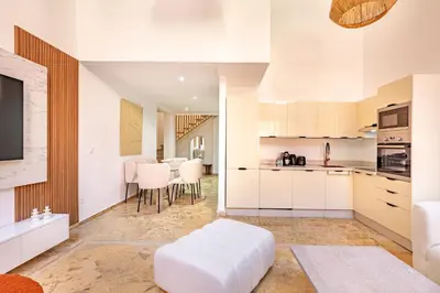 a kitchen with white cabinets and a living room at Duplex Le Majorelle, Res devant le jardin, piscine in Marrakech