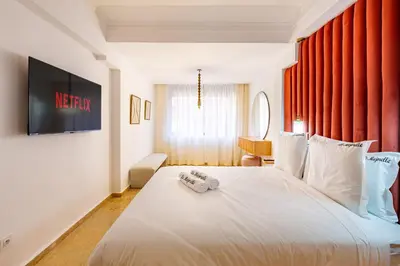 a bedroom with a white bed with a television on the wall at Duplex Le Majorelle, Res devant le jardin, piscine in Marrakech
