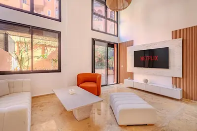 a living room with a couch and a tv at Duplex Le Majorelle, Res devant le jardin, piscine in Marrakech