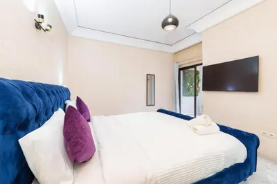 a bedroom with a white bed with purple pillows at Exclusive Stay M-Avenue Marrakech in Marrakech