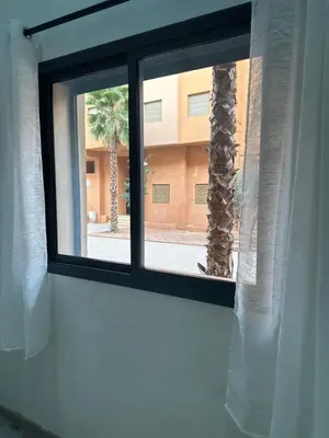 a window with a view of a palm tree at La Citrine appartement de haut standing in Marrakech
