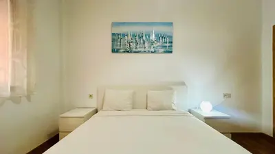a bedroom with a white bed with a painting on the wall at le saphir un appartement de paradis in Marrakech