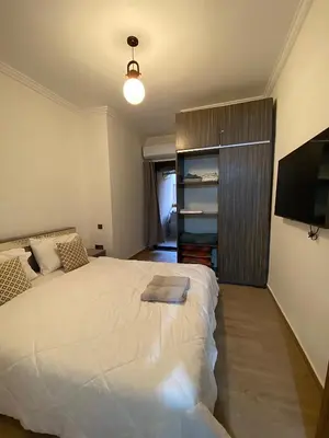 a bedroom with a large white bed and a television at Appart26 Marrakech guéliz en face la Gare in Marrakech