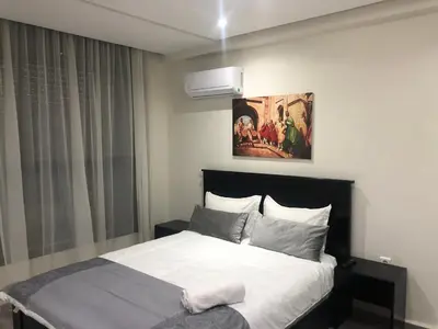 a bedroom with a bed and a painting on the wall at Modern apartment centre ville in Marrakech