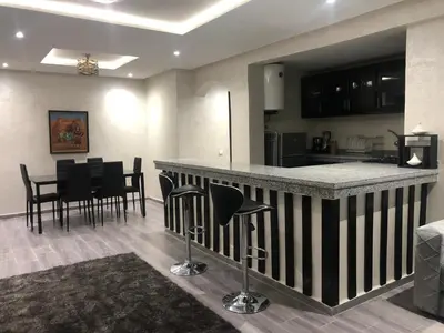 a kitchen and living room with a bar and chairs at Modern apartment centre ville in Marrakech