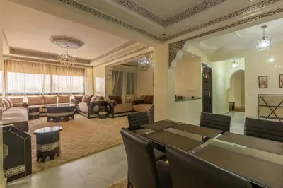 a dining room and living room with a table and chairs at Elegant apartment downtown in Marrakech