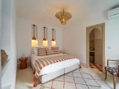 a bedroom with a bed and a chandelier at Riad Dar Victoire in Marrakech